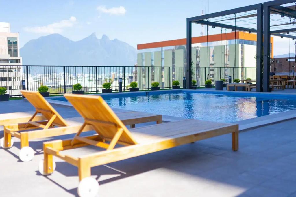 2 sillas, una mesa y una piscina en un edificio en Lux 2 bedroom apartment, swimming pool, gym and free parking spot in Macro Plaza area, en Monterrey