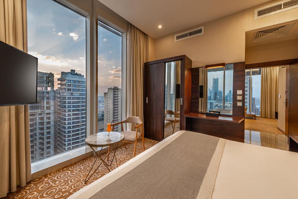 a hotel room with a bed and large windows at Crown Rose AlSahafa Hotel in Riyadh