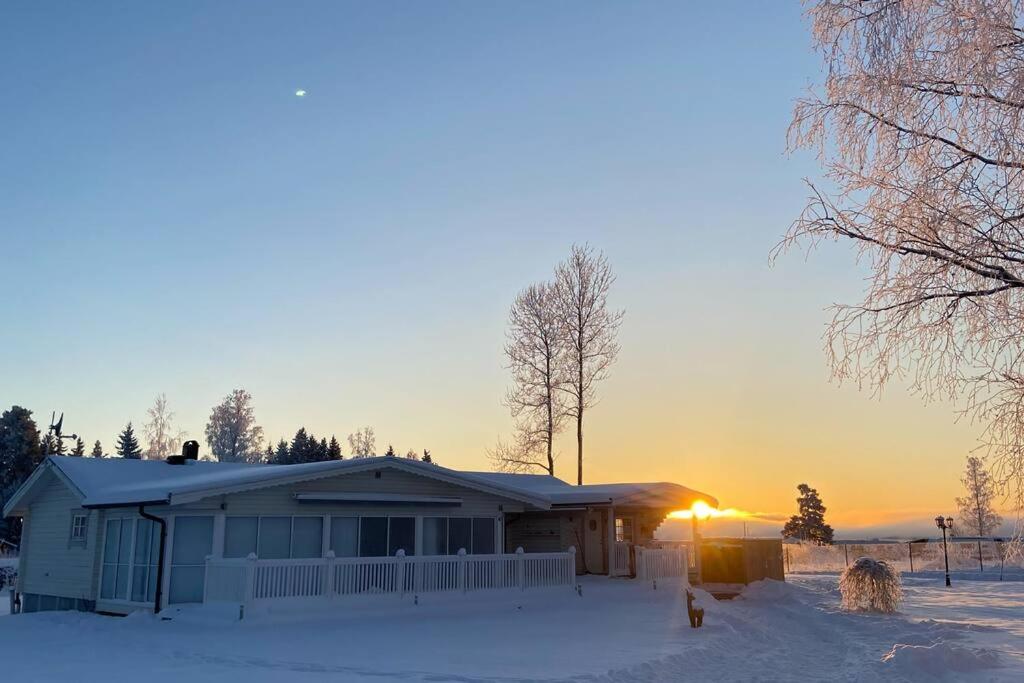 ein Haus im Schnee mit Sonnenuntergang im Hintergrund in der Unterkunft Mysigt hus i Torsby in Torsby