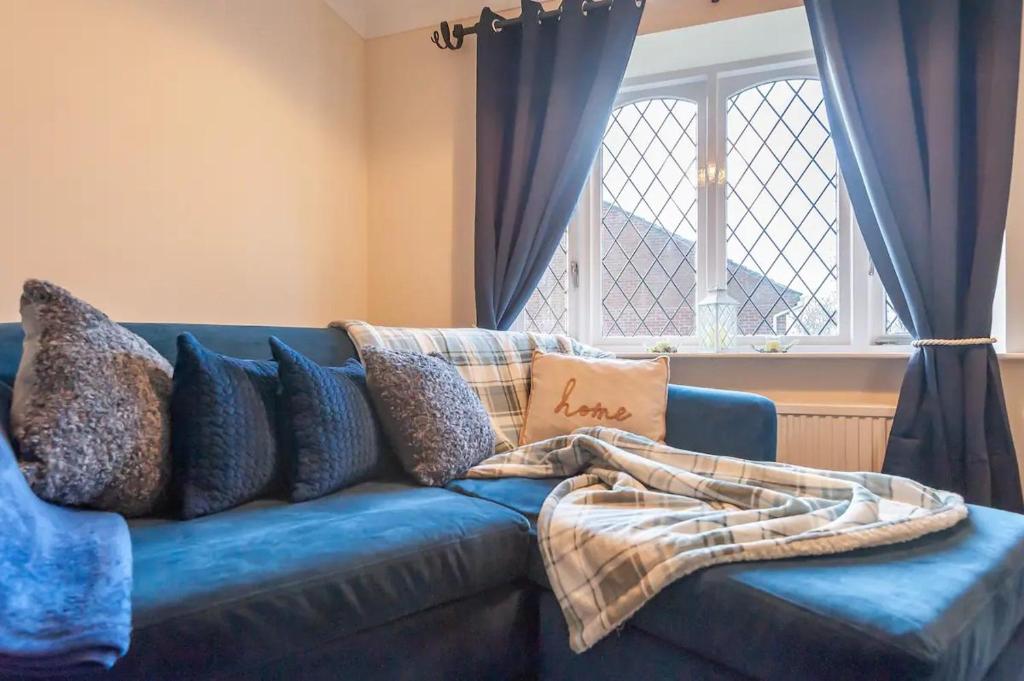 a blue couch in a living room with a window at Pass the Keys Cosy Haven next to White Rose Shopping Centre in Leeds
