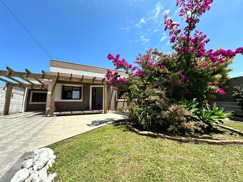 uma casa com flores cor-de-rosa no quintal em Excelente localização a metros do mar e próximo a todos os recursos em Xangri-lá