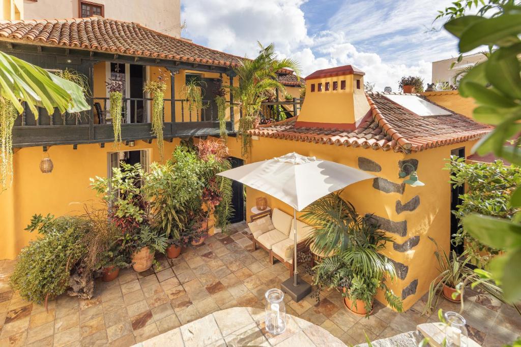 een geel huis met een paraplu op een patio bij Hotel San Telmo in Santa Cruz de la Palma