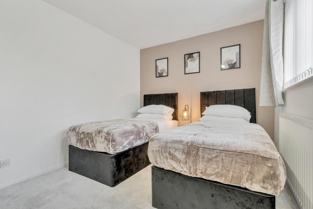 two beds in a bedroom with white walls at Opulent Contractor Stay in Birmingham