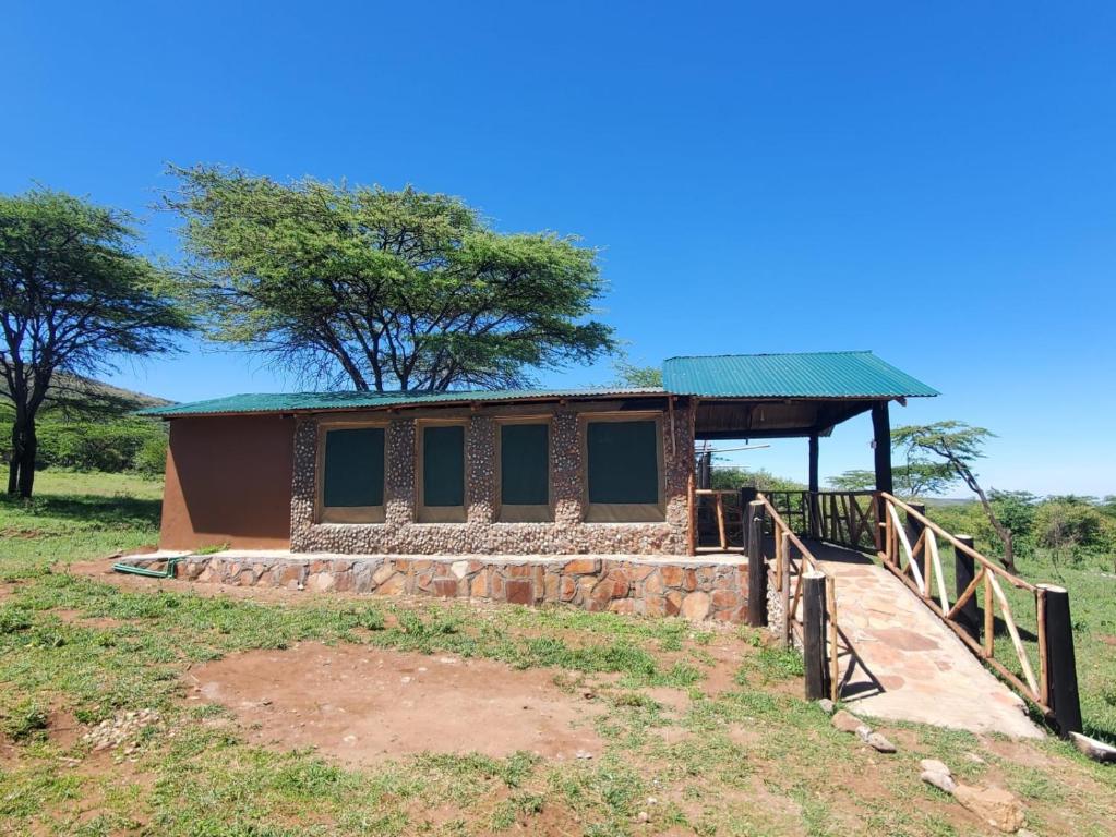 ein kleines Gebäude mit einem grünen Dach auf einem Feld in der Unterkunft ilkerin camp maasai mara in Sekenani