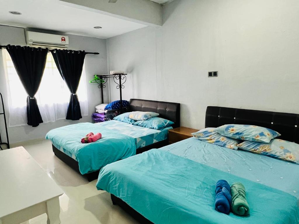 two beds in a room with blue sheets at Sehijau Homestay Kangar in Kangar