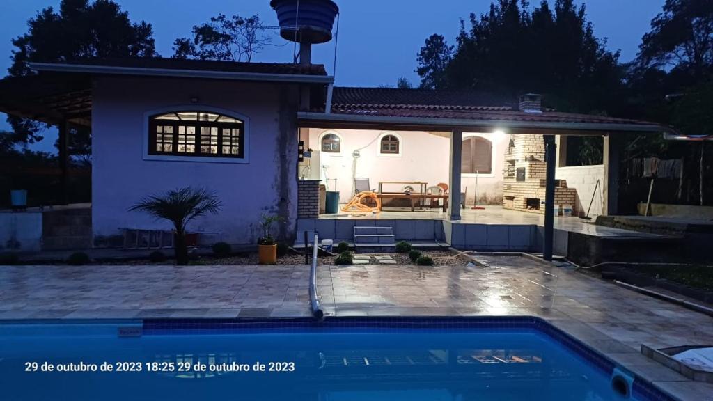 uma casa com uma piscina em frente em casa rosa em Cotia