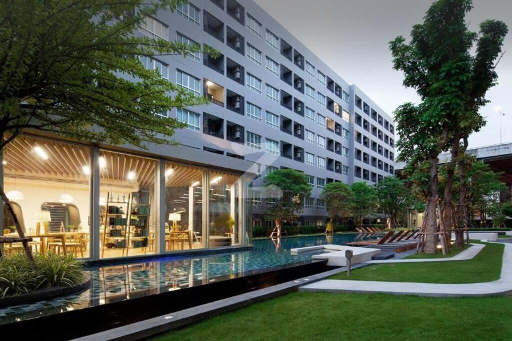 een groot gebouw met een zwembad ervoor bij Elio Sukhumvit 64: Chic Space in Bangkok