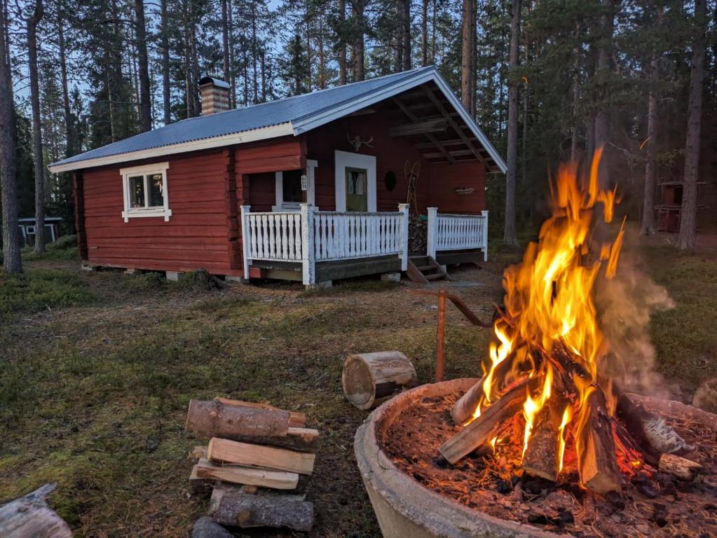a fire pit in front of a cabin at Pine Tree Cabin in Glommersträsk
