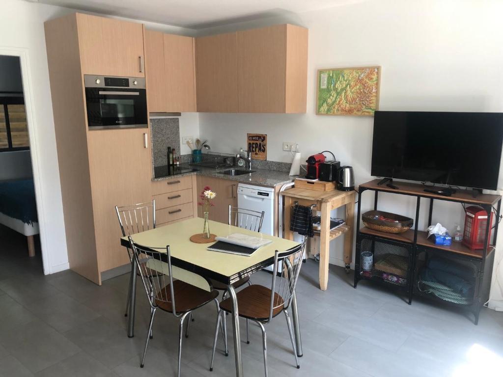 a kitchen with a table with chairs and a television at Les Ateliers de la Villette Meublé de tourisme classé 2 étoiles T3 in La Ravoire