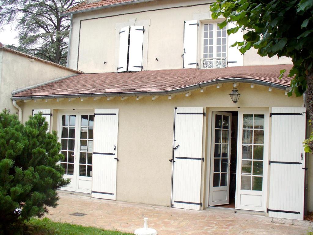 una casa con puertas y ventanas blancas en Maison d'Hôtes Villa Brindille, en Bois-le-Roi