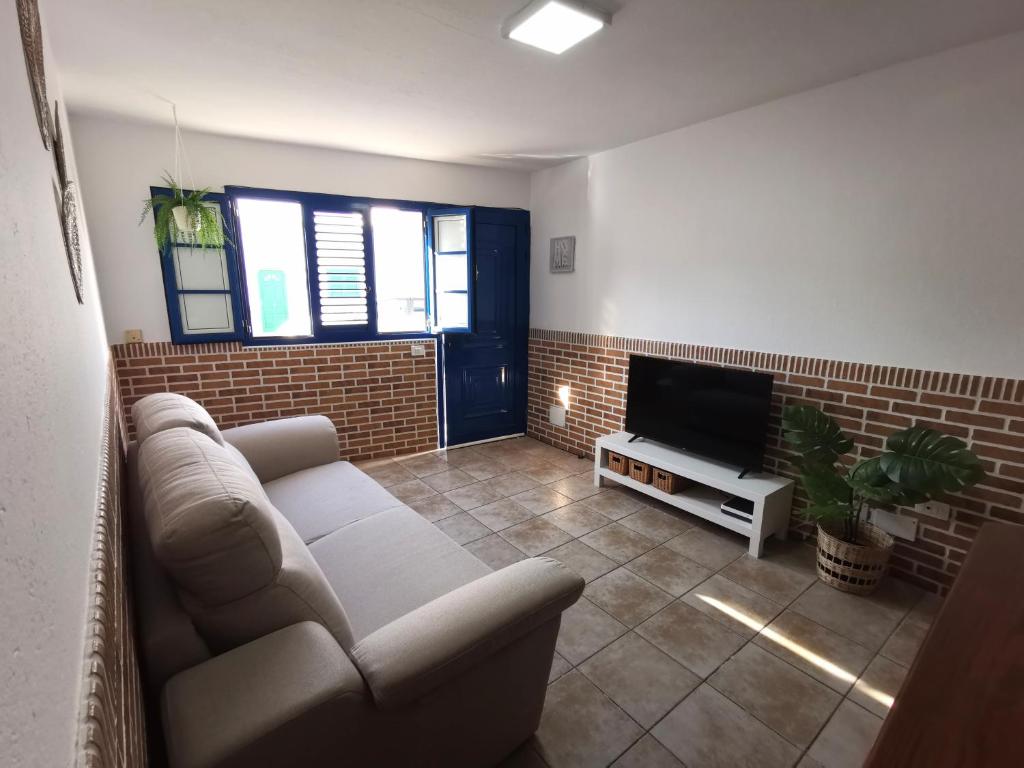 uma sala de estar com um sofá e uma televisão de ecrã plano em Apartamento La Condesa em Orzola