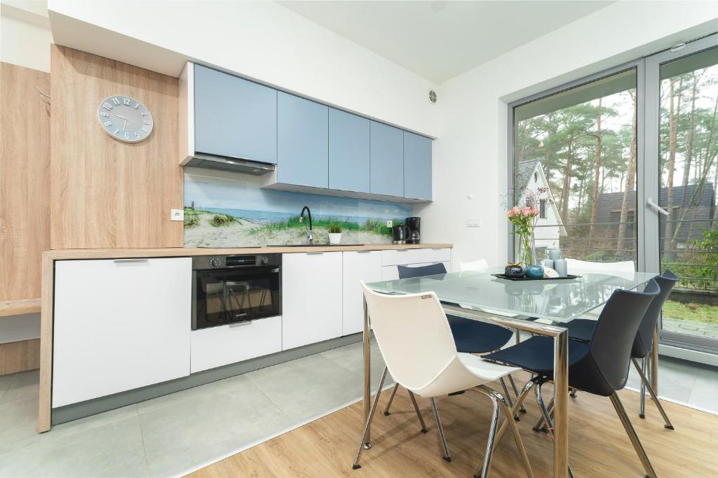 a kitchen with white cabinets and a table and chairs at Apartament Niebieski c4 in Pobierowo