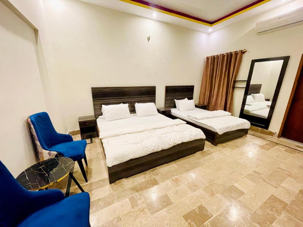 1 dormitorio con 2 camas y silla azul en Airport Hotel Bed & Rest en Karachi