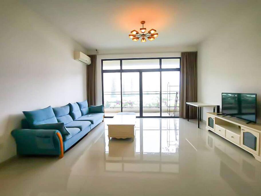 ein Wohnzimmer mit einem blauen Sofa und einem TV in der Unterkunft ForestCity Cerulean Bay 4 Room Near Duty Free Shop in Kampong Tanjong Kupang
