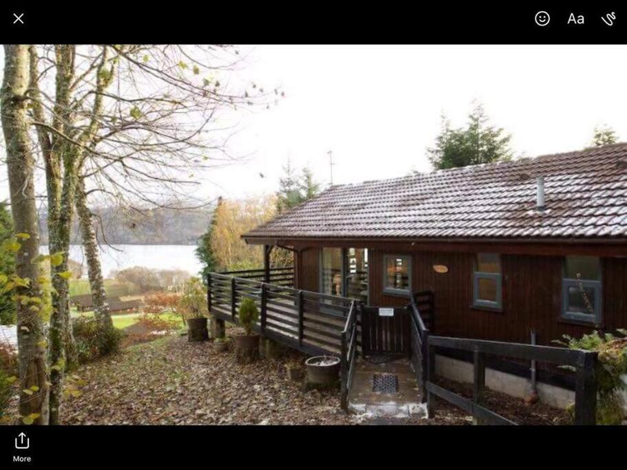 a wooden cabin with a porch and a fence at The Crannog on Loch Tay in Morenish