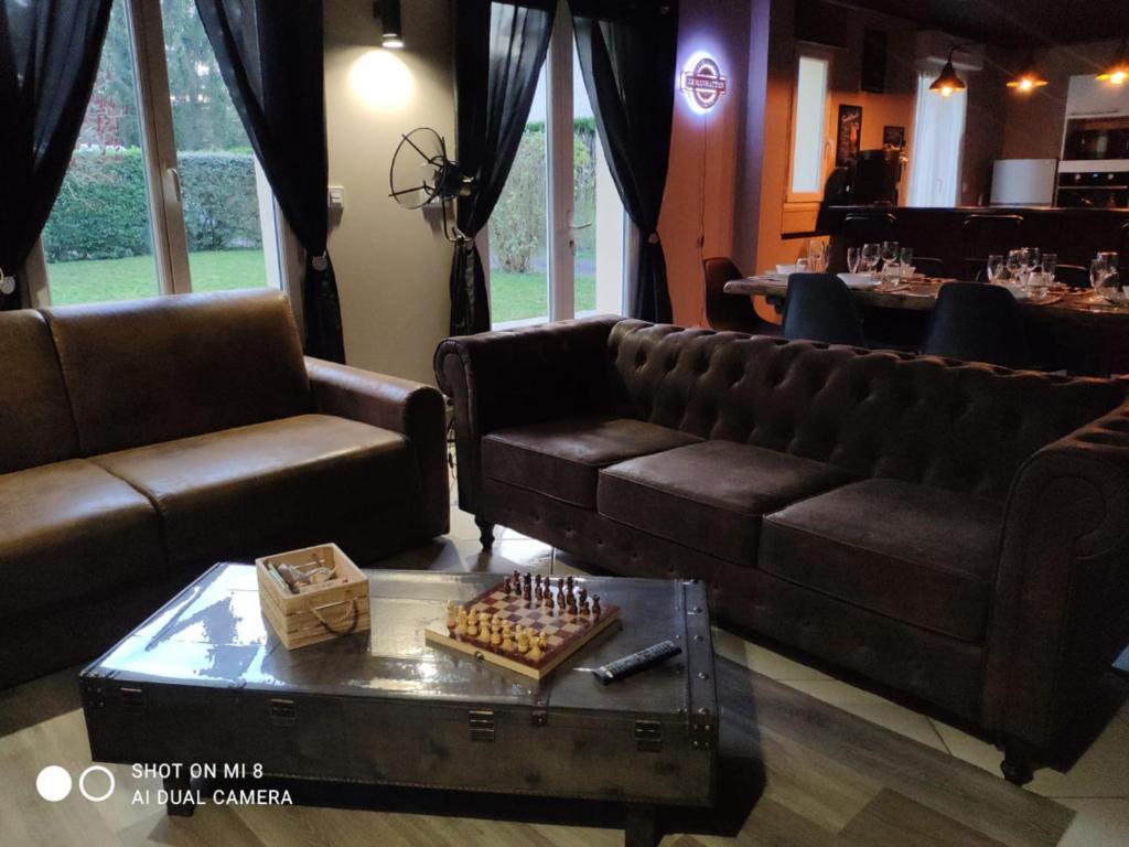 sala de estar con 2 sofás y mesa con tablero de ajedrez en LE MANHATTAN Authentique maison climatisée 78 m2, en Brasles