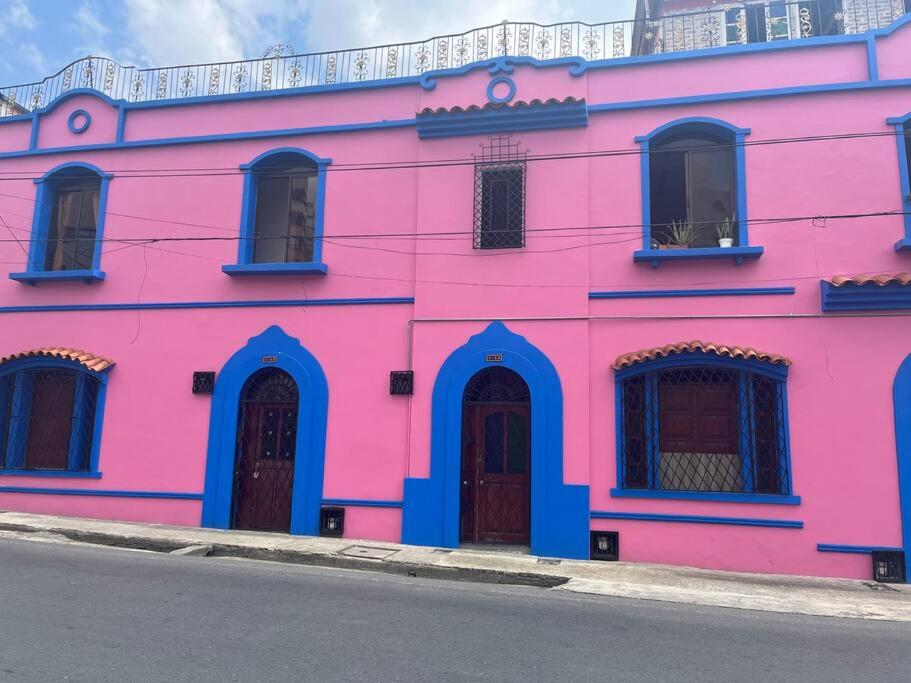 a pink building with blue doors and windows at Casa colonial Rosa San Antonio in Cali