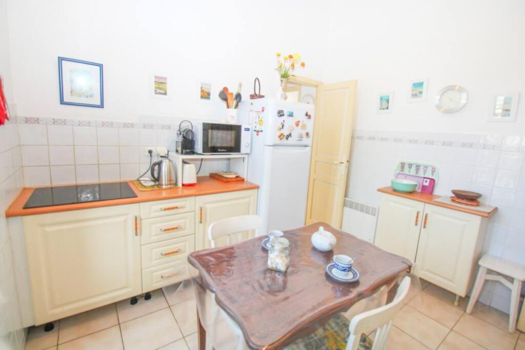 a small kitchen with a table and a refrigerator at Pavillon de Mer YourHostHelper in Vallauris