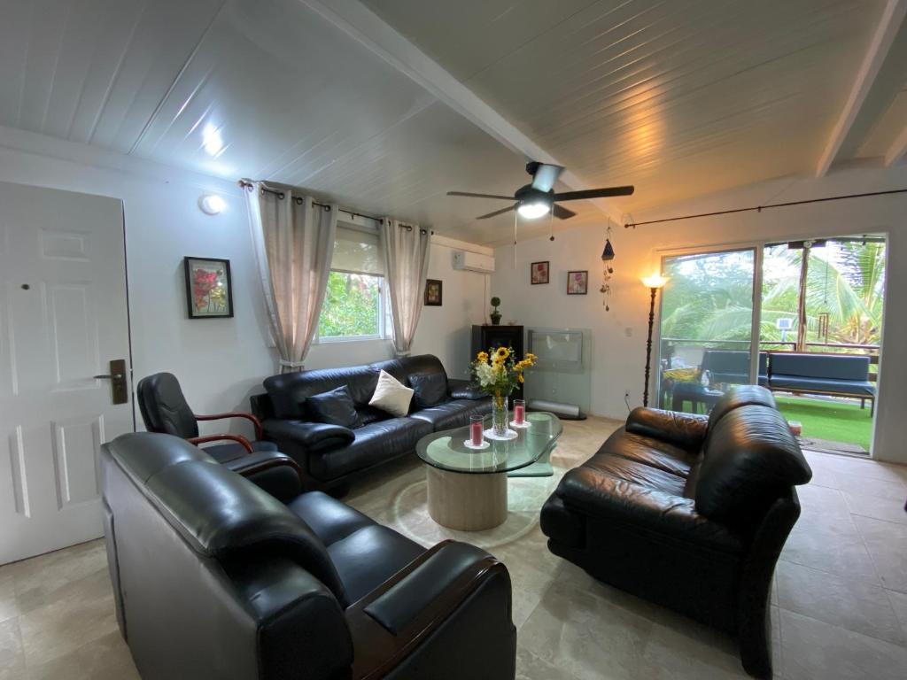 a living room with leather furniture and a ceiling fan at Aeolus Guest House in José Pobre