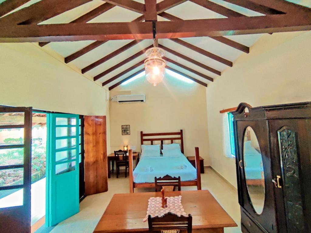 ein Schlafzimmer mit einem Bett und einem Tisch in einem Zimmer in der Unterkunft The Bungalow Bogmalo An 1880 Indo Portuguese Heritage Beach Villa South Goa in Bogmalo Beach