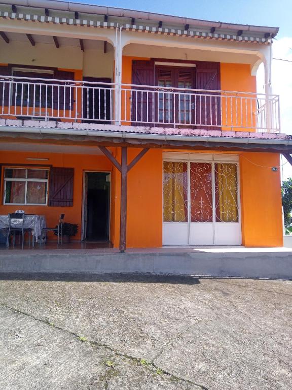 Casa de color naranja con balcón y mesa en Mornes Caraïbes en Vieux-Habitants