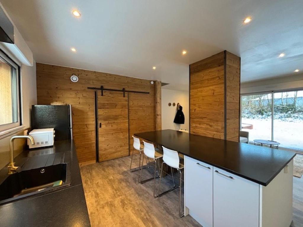 a kitchen with a black counter and some chairs at Duplex le Red Cedar avec terrasse et jardin in Gérardmer