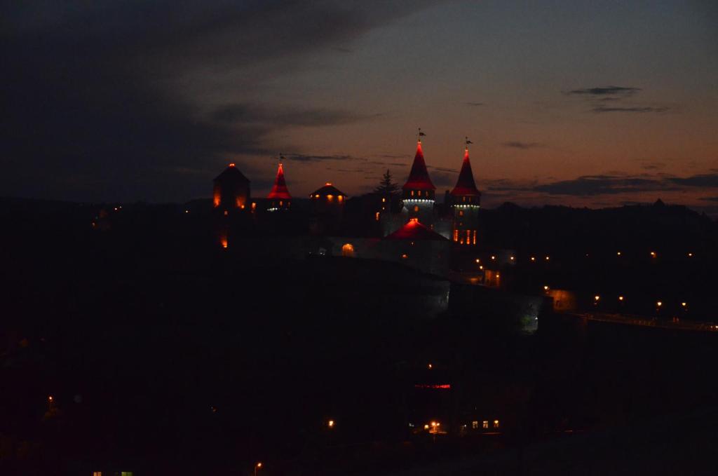 a night view of a castle with red roofs at Brama Ruska in Kamianets-Podilskyi