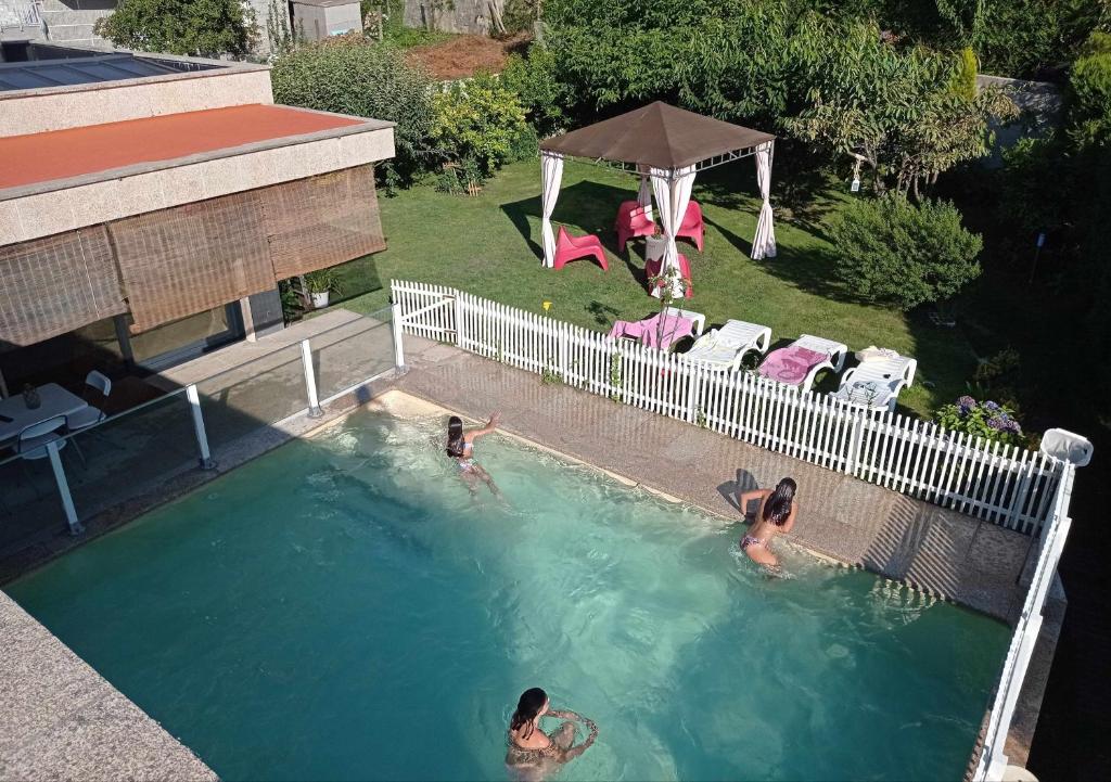duas pessoas estão a nadar numa piscina em Chalet con piscina y diversión Ría de Vigo em Vilaboa