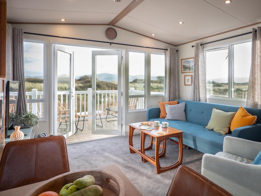 伯斯的住宿－Little Curlew, Ynyslas, Borth，一间带蓝色沙发的客厅和一个阳台