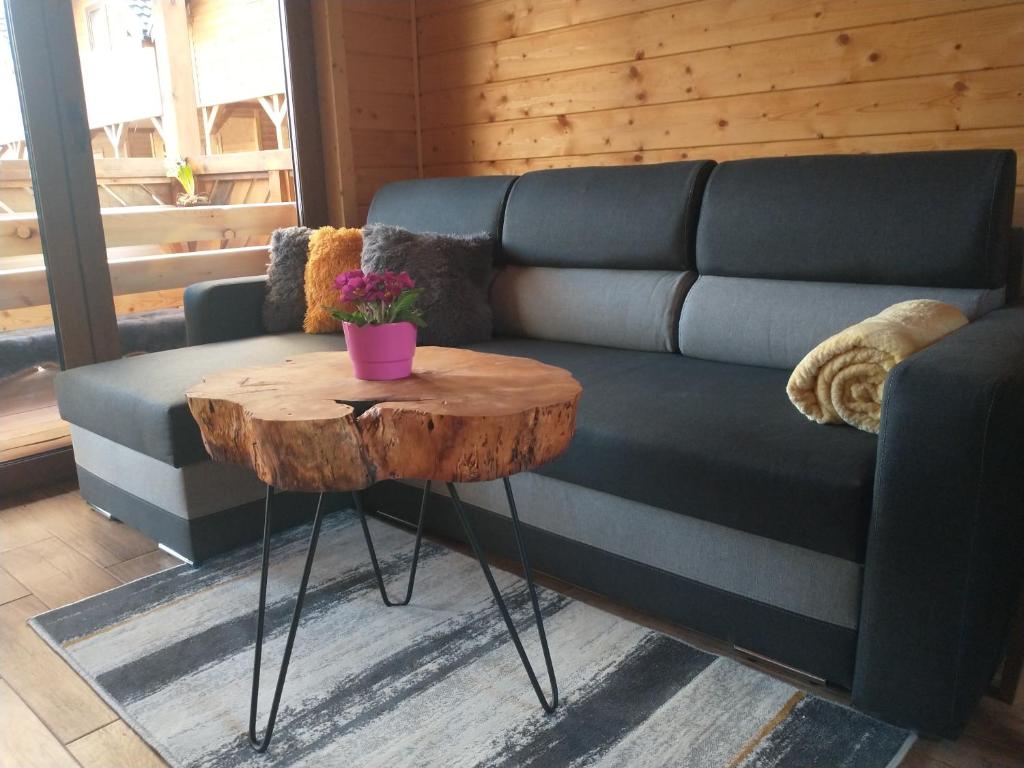 uma sala de estar com um sofá azul e uma mesa de madeira em Domki u Magdaleny em Sztutowo