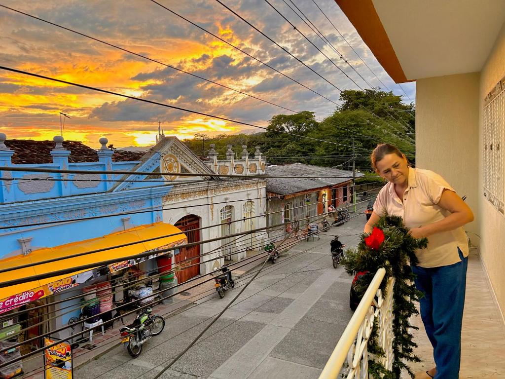 a man is standing on a balcony with flowers at Casa Hotel Los Fundadores in La Victoria