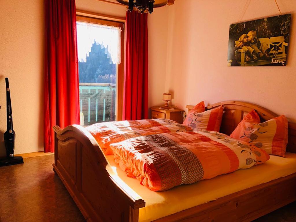 a bed in a bedroom with a window with red curtains at Egghof in Prato allo Stelvio