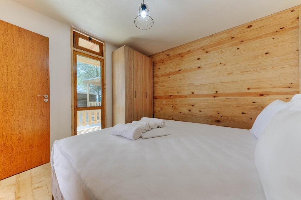 1 dormitorio con cama blanca y pared de madera en Family Bungalows en Ulcinj