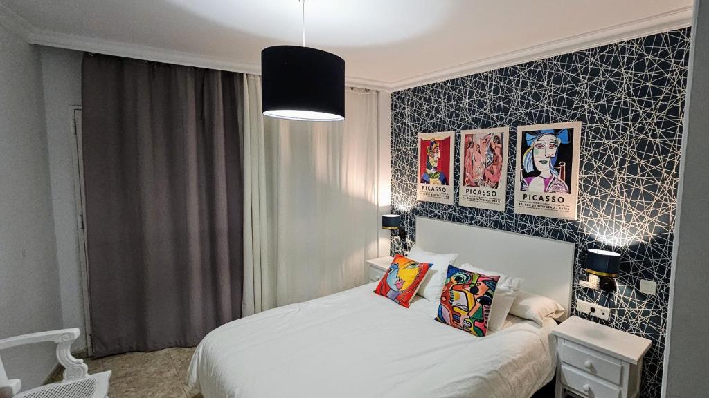 1 dormitorio con 1 cama y algunas fotos en la pared en Hostal Luna de Nerja, en Nerja
