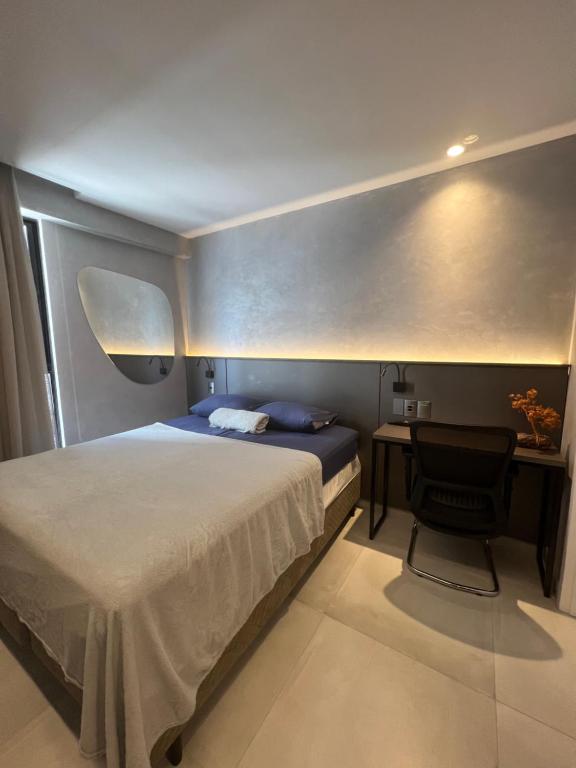 um quarto com uma cama e uma secretária com uma cadeira em FLAT aconchegante e moderno, 100m do mar em Cabedelo