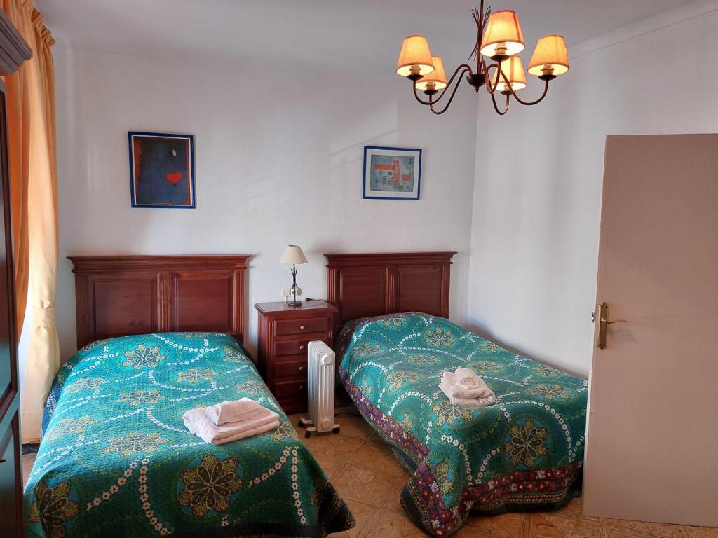 a bedroom with two beds and a chandelier at CASA JARO in Sierra de Yeguas