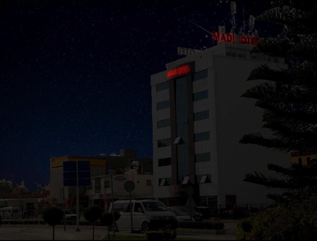 a building with a red sign on top of it at Otel Madi in Seyhan