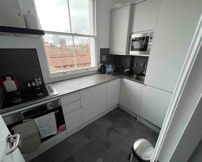 eine kleine Küche mit weißen Schränken und einem Fenster in der Unterkunft 2 Bed Apartment in Central London on 3rd floor - Newly refurbished - No lift in London