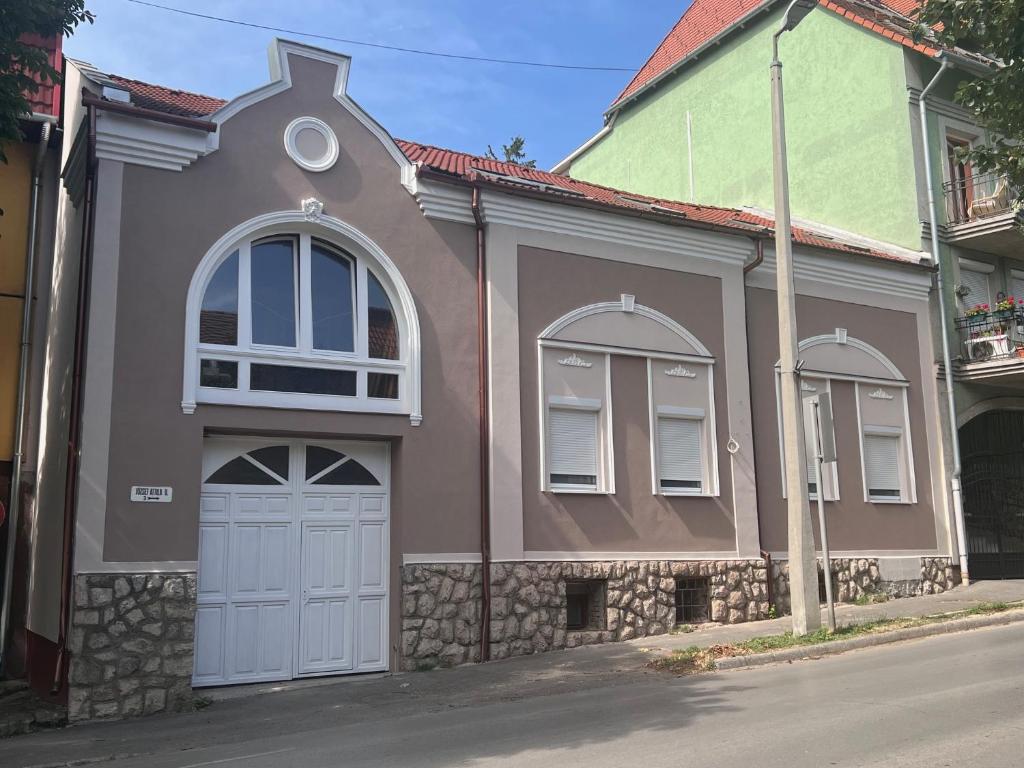 a brown and green house with a garage at Berzsenyi Apartmanház in Kaposvár