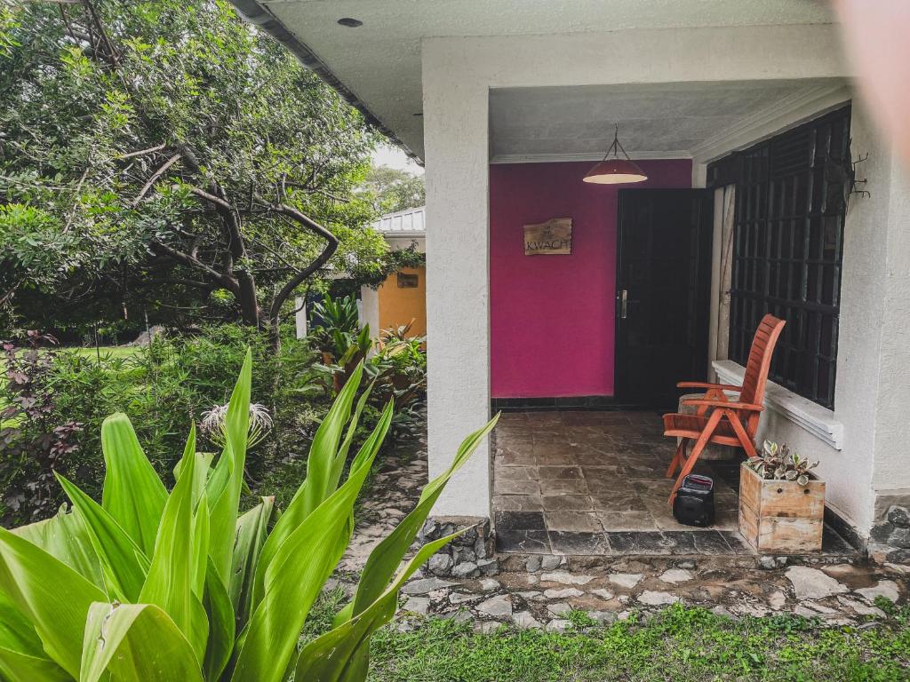 ein Haus mit einer rosa Tür und einem Stuhl auf einer Veranda in der Unterkunft PachobyDaisy in Awasi
