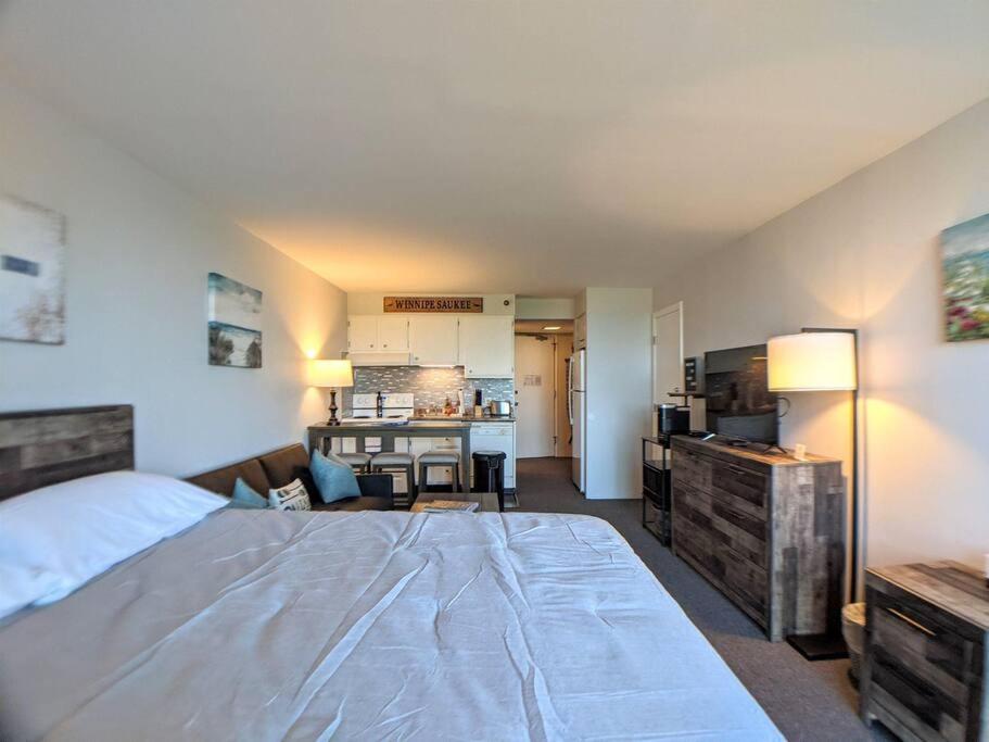 Il comprend une chambre avec un grand lit et une cuisine. dans l'établissement Cute Cedar Lodge Studio with Balcony & Lake Views!, à Laconia