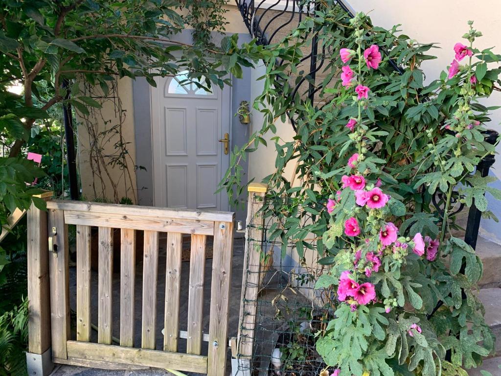 a wooden gate with pink flowers in front of a door at Tournicolette - 52 m2 charme fou in Chardonne