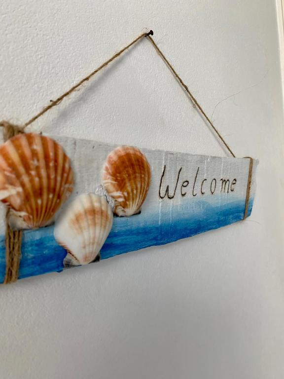 a welcome sign with two seashells on a wall at Aegean Aura Apartment II in Kalymnos