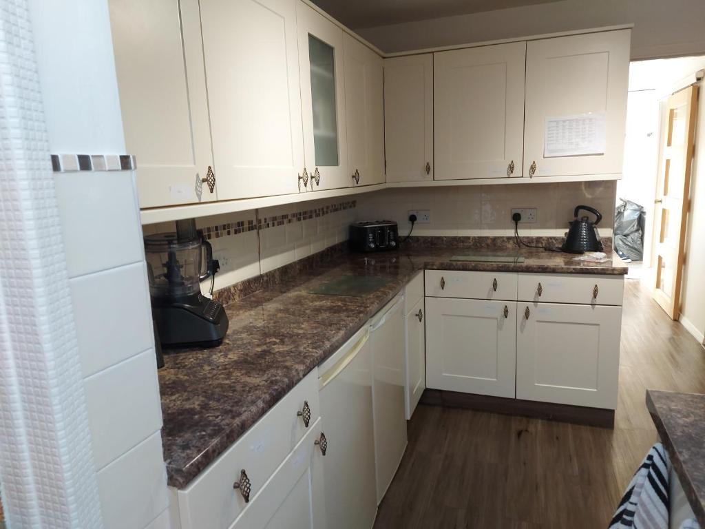 a kitchen with white cabinets and marble counter tops at Ensuite room The bungalow William Harvey hospital in Willesborough