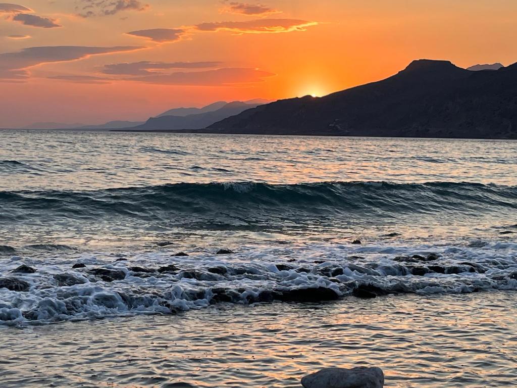einen Sonnenuntergang am Strand mit einem Berg im Hintergrund in der Unterkunft Villa View- Grapevines Villas - your sea view vacation in Makry Gialos