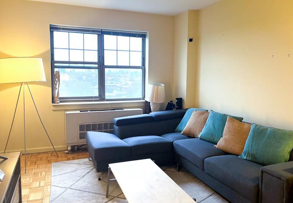 sala de estar con sofá azul y ventana en Gorgeous 2 Bedroom apartment in NYC!, en Nueva York