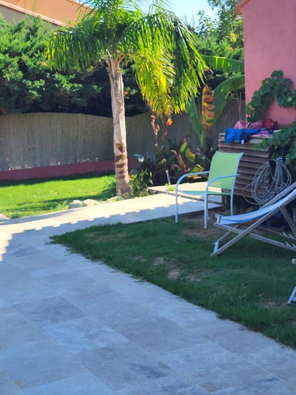 a patio with chairs and a palm tree in a yard at Maison avec jardin arboré in Saint-Nazaire