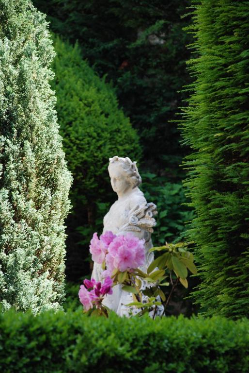 une statue d'une femme avec des fleurs roses dans un jardin dans l'établissement Hôtel particulier Maleteste, à Dijon