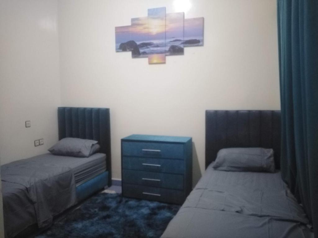 1 dormitorio con 2 camas, vestidor y una pintura en Appartement du lux très propre bien équipé au cœur de la ville nouvelle, en Meknès