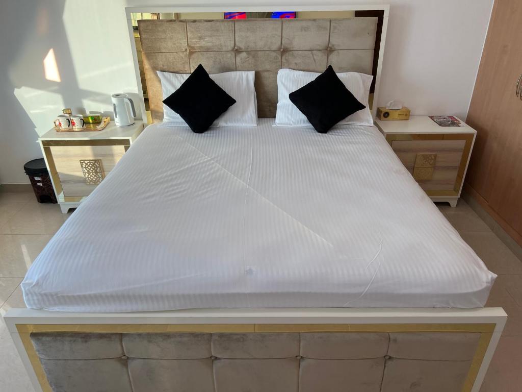 1 dormitorio con 1 cama blanca grande con almohadas negras en Ft 30f R2 SeaView Room at Beach with separate bath en Ajman 